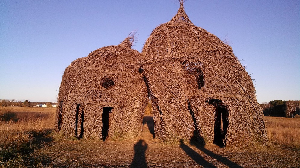 "Lean on Me," a Stickworks art installation by Patrick Dougherty - woven stick chapel-like structures leaning against each other.