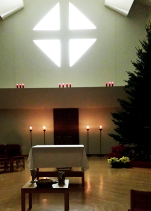 candle light and plain, bare Christmas tree await Christmas Eve services in the assembly room