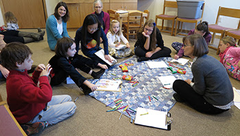 Children & adults gathered together, sitting on the floor