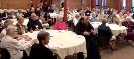 Sisters, monks and others gathered at tables for presentations and conversation. 